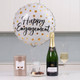 Happy Engagement Balloon & Bubbles Gift. A white and gold polka dot balloon displays the text "Happy Engagement." Beside it, a bottle of champagne stands next to a glass filled with champagne. In the foreground, there is a box of chocolates and a small bag of treats. The setting features a modern kitchen background. Happy Engagement Balloon & Bubbles Gift. A white and gold polka dot balloon displays the text "Happy Engagement." Beside it, a bottle of champagne stands next to a glass filled with champagne. In the foreground, there is a box of chocolates and a small bag of treats. The setting features a modern kitchen background.